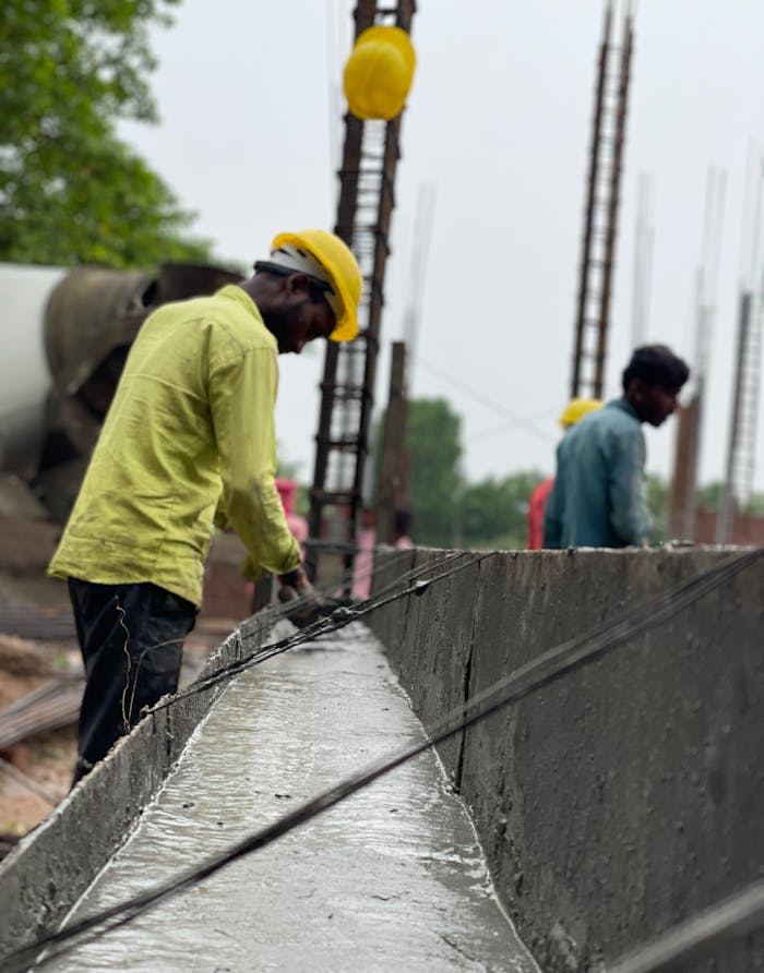 mission-02 Men at work on a construction site, focusing on concrete tasks, wearing safety gear.